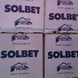 Stos palet z zapakowanymi bloczkami SOLBET, widoczne logo producenta i adres strony internetowej na opakowaniach.